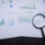 Magnifying glass and documents with analytics data lying on table